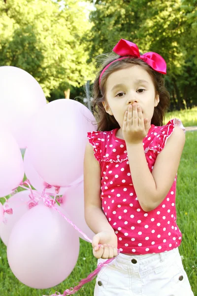 Menina no parque com balões cor de rosa — Fotografia de Stock