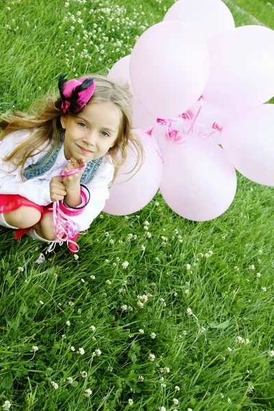 Klein meisje in het park met roze ballonnen — Stockfoto