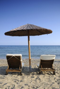 plaj şemsiyesi ve denize iki sandalye