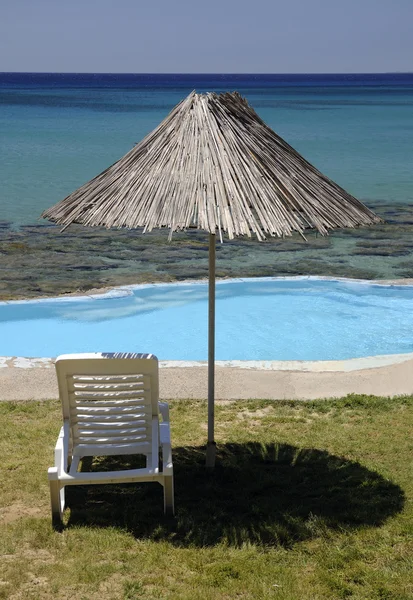 Tumbona y sombrilla sobre la piscina — Foto de Stock