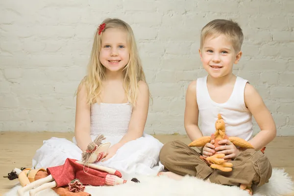 Sorridente fratelli bambini che giocano con animali di peluche — Foto Stock