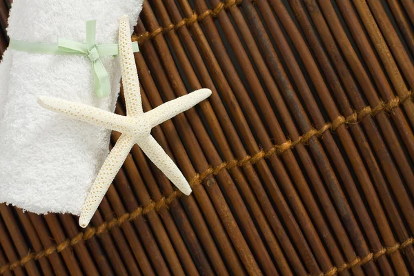 Spa ou fundo de bem-estar com toalha branca na esteira de bambu — Fotografia de Stock