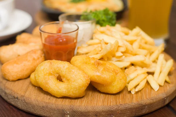 Snack - fried potatoes and squid in restaurant — Stock Photo, Image
