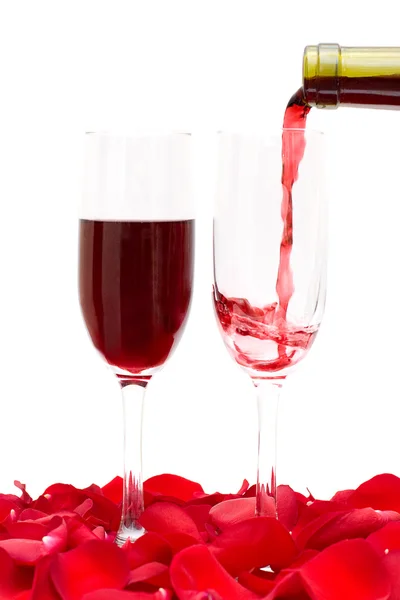 Twee glas wijn en rood roze bloemblaadjes geïsoleerd op witte achtergrond — Stockfoto