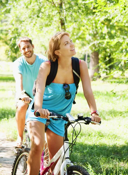 Jovem casal feliz andando de bicicleta — Fotografia de Stock