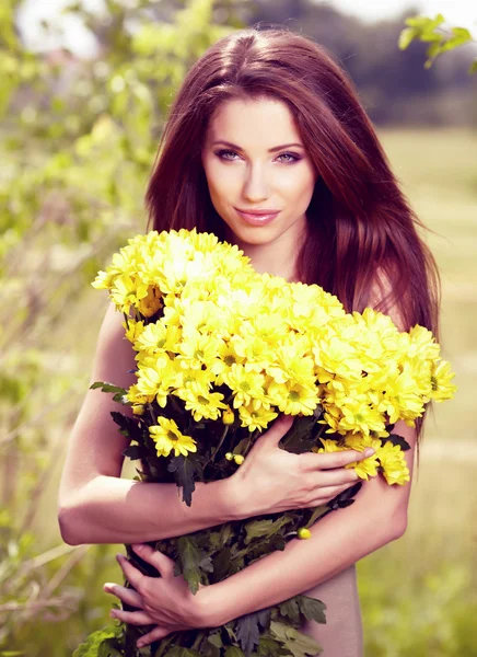 Vrouw bedrijf gele bloemen. Otdoor schieten — Stockfoto