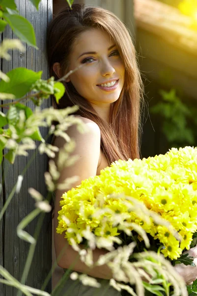 .Hermosa mujer relajándose en el jardín. Sostiene flores amarillas —  Fotos de Stock