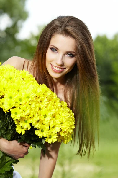 Fiatal nő gazdaság sárga virágok — Stock Fotó