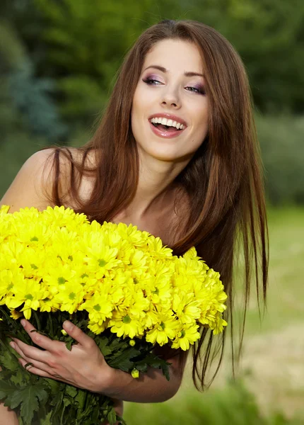 Jeune femme tenant des fleurs jaunes — Photo