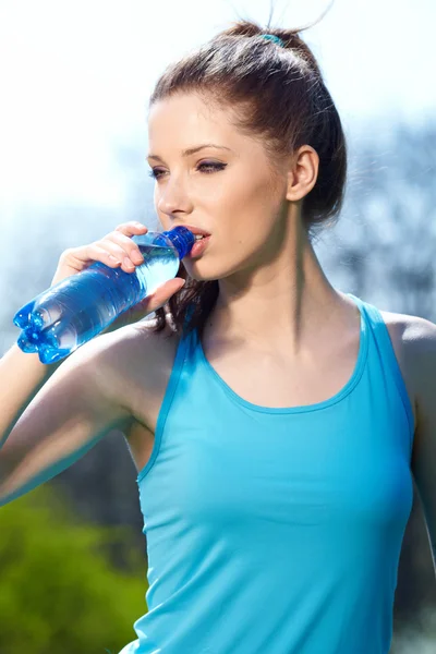 Giovane donna che beve acqua all'aperto allenamento — Foto Stock