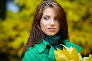Sonbahar parkında sarı yaprak tutan moda kadını