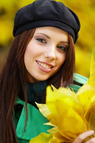Mulher de moda no parque de outono segurando folha amarela — Fotografia de Stock