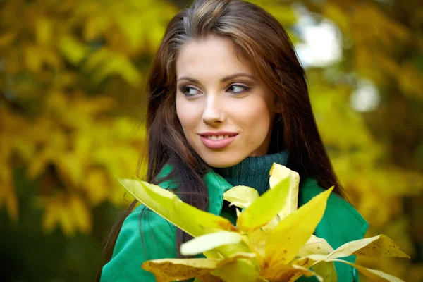 Mode kvinna i höst park håller gula löv — Stockfoto