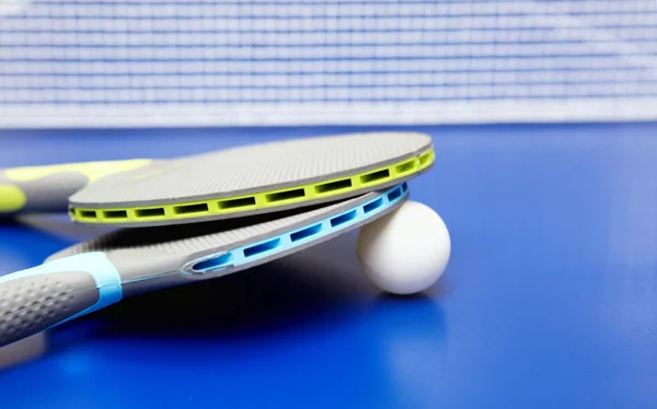 To bordtennis eller ping pong-racketer og baller på et blått bord – stockfoto