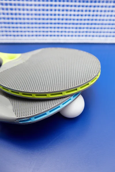 Два настільний теніс або ракетки для пінг-понг і м'ячі на синьому столі — стокове фото