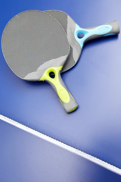 Dos raquetas y pelotas de ping pong o ping pong sobre una mesa azul — Foto de Stock