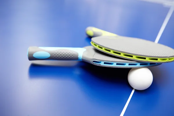Два настольных тенниса или ракетки и мячи для пинг-понга на синем столе — стоковое фото