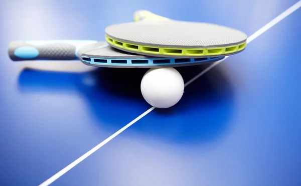 Dos raquetas y pelotas de ping pong o ping pong sobre una mesa azul — Foto de Stock