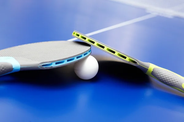 Due racchette da ping pong o da ping pong e palline su un tavolo blu — Foto Stock