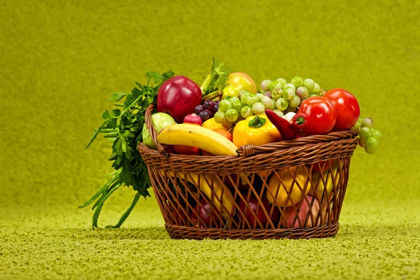 Basket full of fresh produce. green background — Stock Photo, Image
