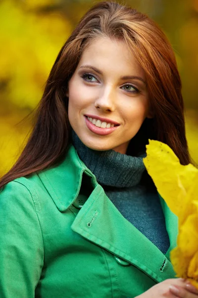 Mujer de moda en el parque de otoño sosteniendo hoja amarilla — Foto de Stock