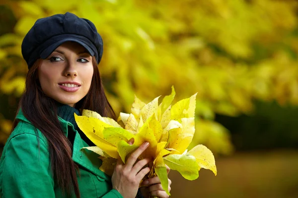 Moda kobieta w jesiennym parku gospodarstwa żółty liść — Zdjęcie stockowe
