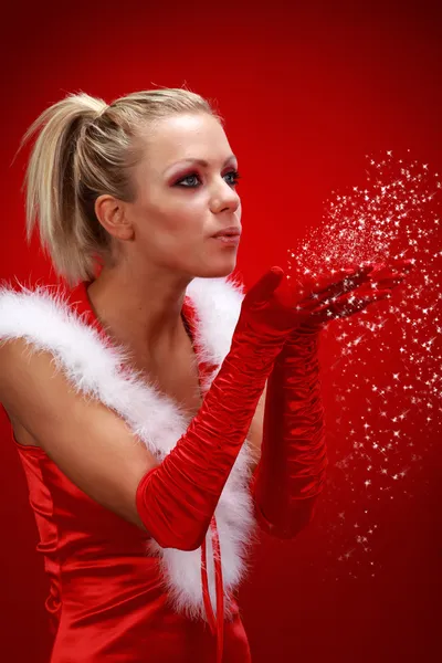 Attraente ragazza sexy in panno di Babbo Natale soffiando neve dalle mani . — Foto Stock