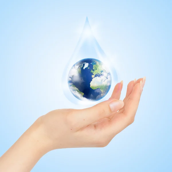 Drop of water with Earth inside and hand — Stock Photo, Image