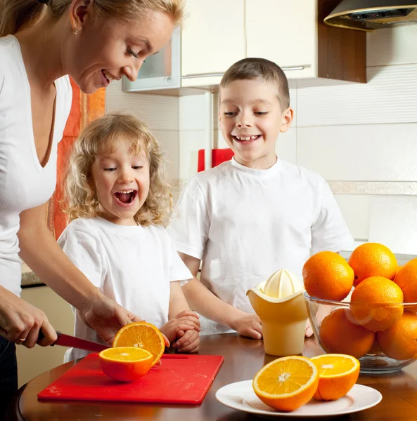 Mãe com crianças espremido suco de laranja — Fotografia de Stock