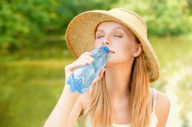 Girl in straw hat drinks water clipart