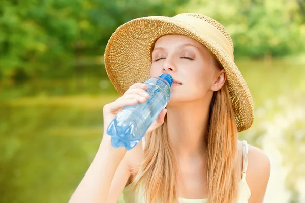 Girl in straw hat drinks water — Stock Photo, Image