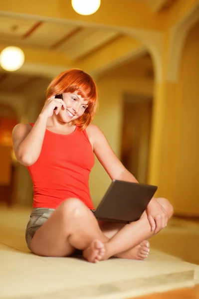Ung kvinna med mobiltelefon och bärbar dator. — Stockfoto