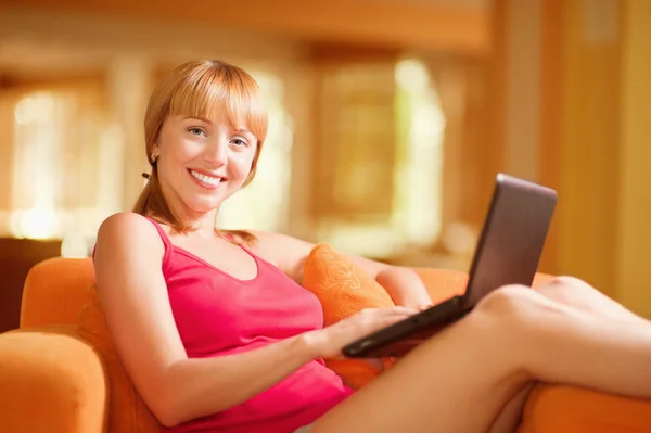 Kvinna sitter på soffan med laptop — Stockfoto