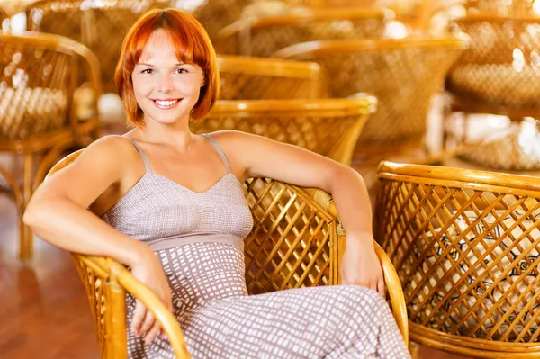 Young woman sits in armchair — Stock Photo, Image