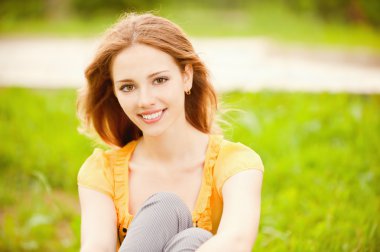 Beautiful girl sits on lawn clipart