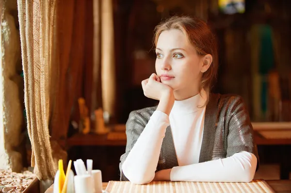 Молода красива жінка сидить у кафе — стокове фото