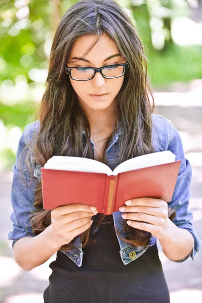 Menina séria lê livro vermelho — Fotografia de Stock