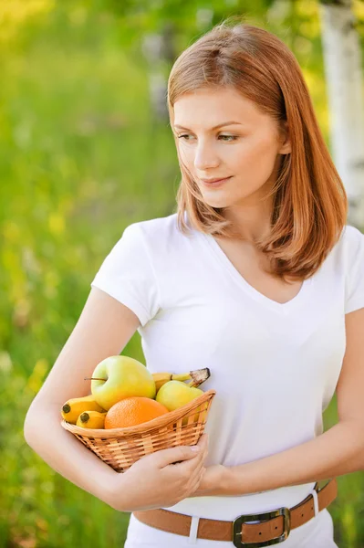 Woman holds basket with fruit — Stock Photo, Image