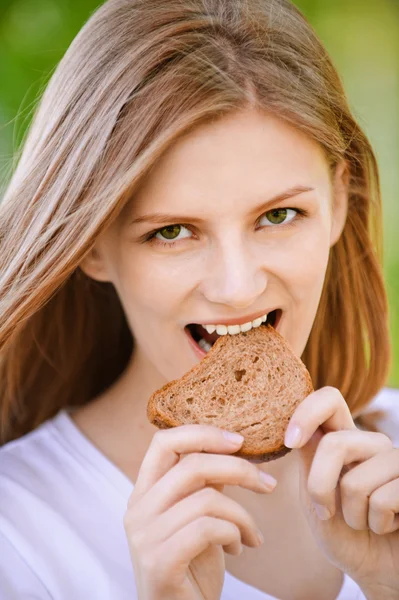 Mulher morde pedaço de pão — Fotografia de Stock