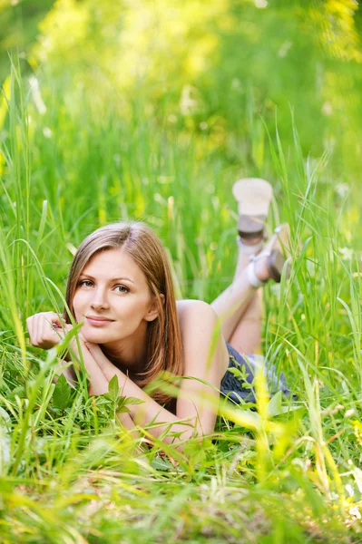 Jovem mulher encontra-se na grama verde — Fotografia de Stock