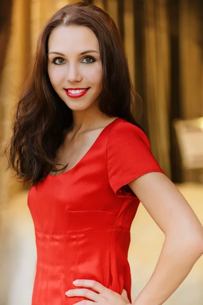 Jonge vrouw in rode jurk glimlachen — Stockfoto