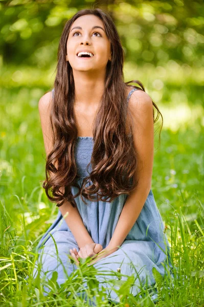 Sorrindo mulher senta-se na grama verde — Fotografia de Stock