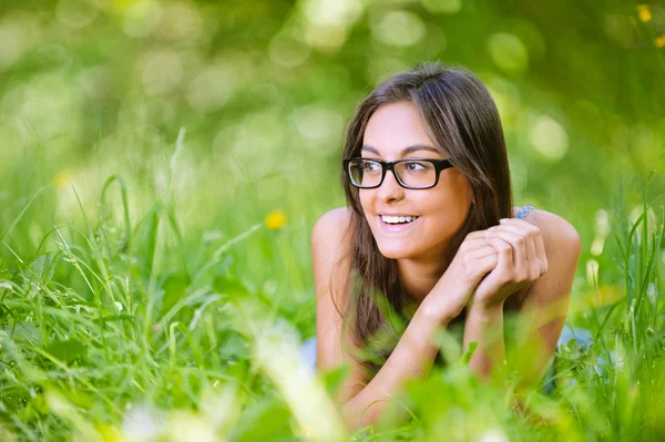 暗い髪の女性は緑の芝生に位置します。 — ストック写真
