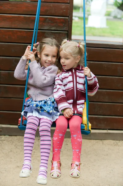 Due ragazze che dondolano nel parco giochi — Foto Stock