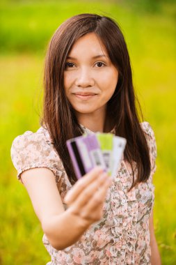 Kredi kartı tutan genç bir kadının portresi.