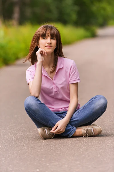 Yol üzerinde oturan genç kadın — Stok fotoğraf