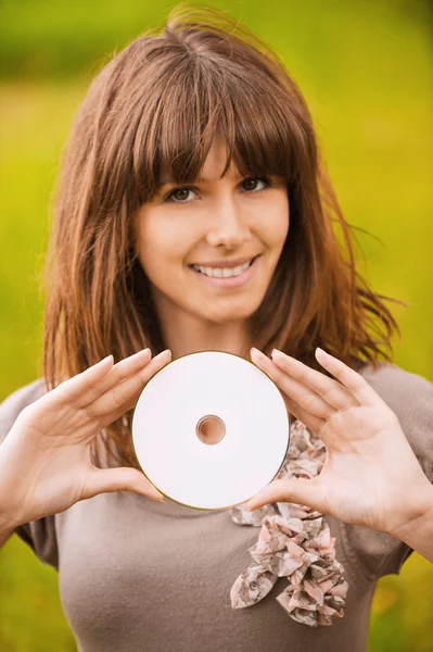 Mladá usměvavá žena drží kompaktní disk — Stock fotografie