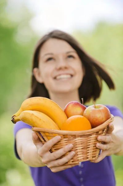 Jonge lachende vrouw met mand met fruit — Stockfoto