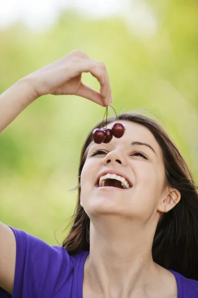 Молодая веселая женщина ест вишни — стоковое фото