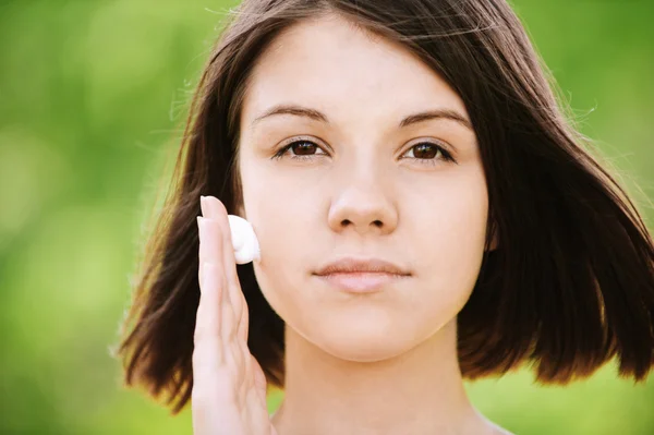 Jonge vrouw zetten crème op haar gezicht — Stockfoto